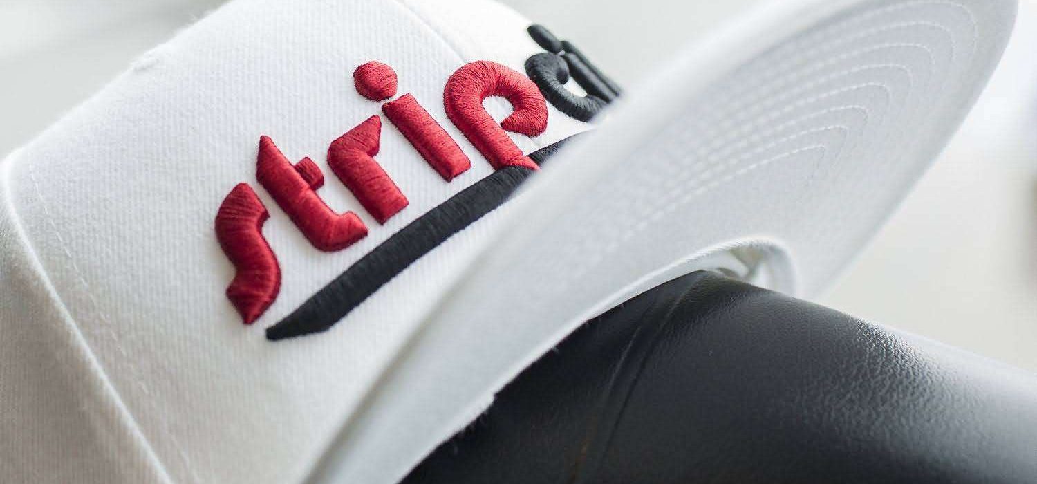 custom-white-snapback-3d-embroidery-streetwear. Custom white snapback cap with red 3D puff embroidery and black flat embroidery text, streetwear style