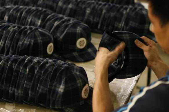 Custom hat quality control: factory worker inspecting custom headwear for precision