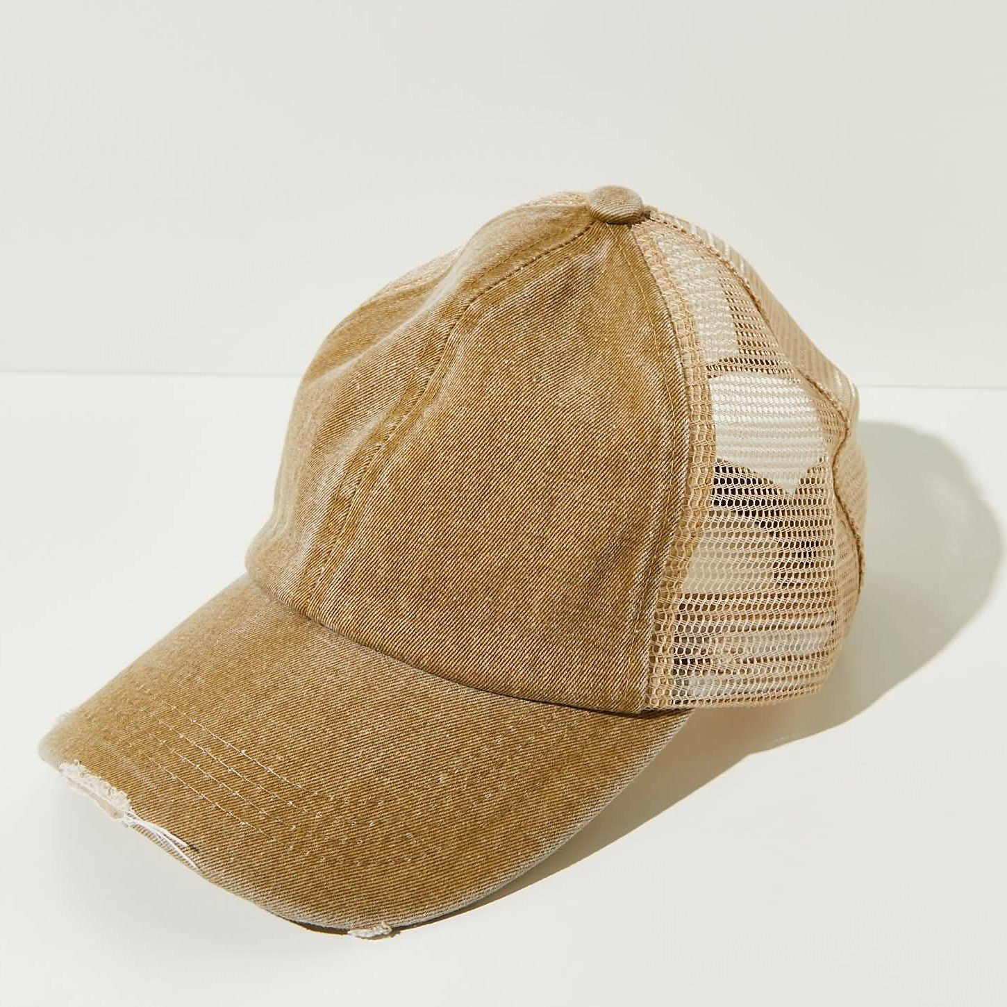 Front profile of a distressed structured cotton trucker hat featuring machine-frayed brim details and stone-washed color fading.