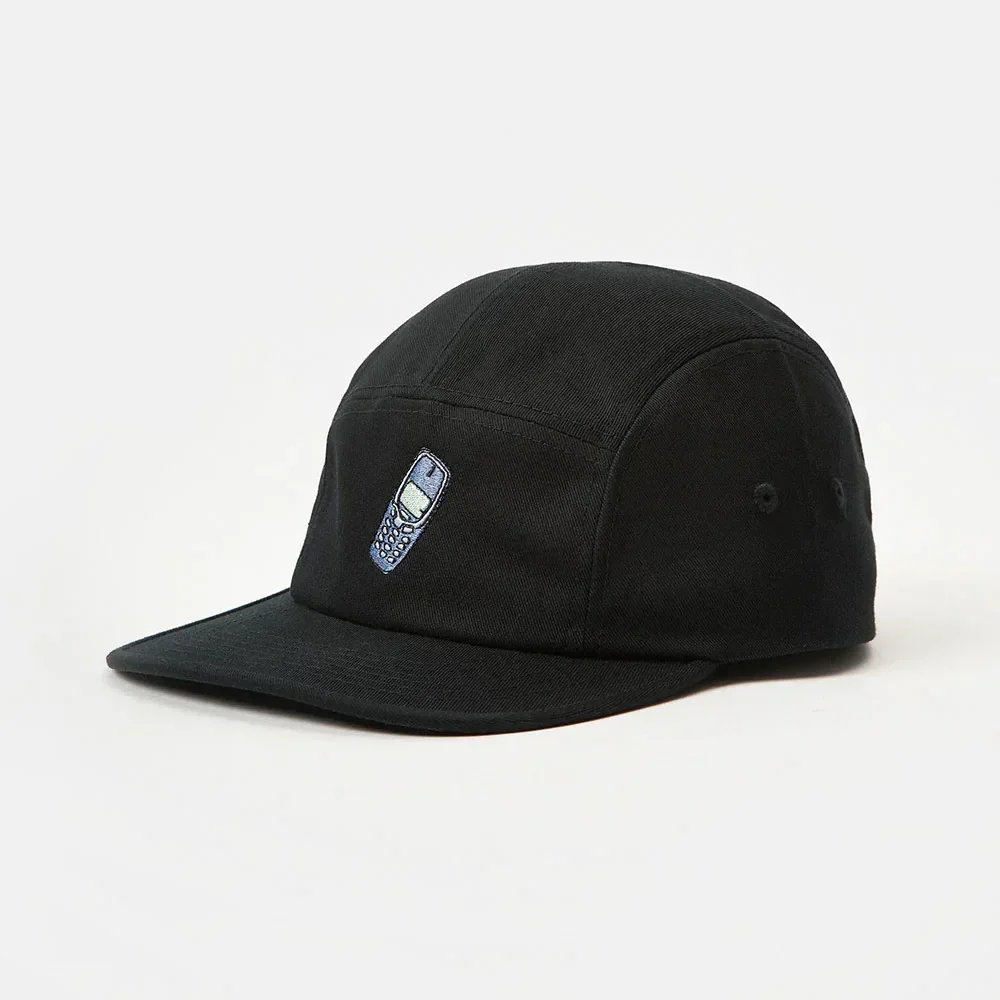 Macro close-up of detailed flat embroidery depicting a blue and green retro mobile phone on black twill fabric of a 5-panel cap.