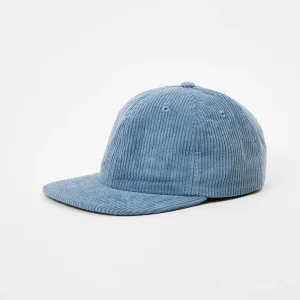 Angled front view of an unstructured blue corduroy 6-panel cap featuring a flat brim, ribbed fabric texture, and tonal stitched eyelets.