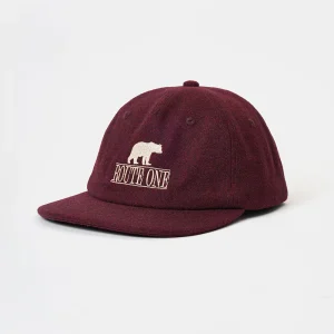 Angled front view of an unstructured burgundy wool melton 6-panel dad hat featuring a flat brim and crisp high-density beige "Route One" bear embroidery.