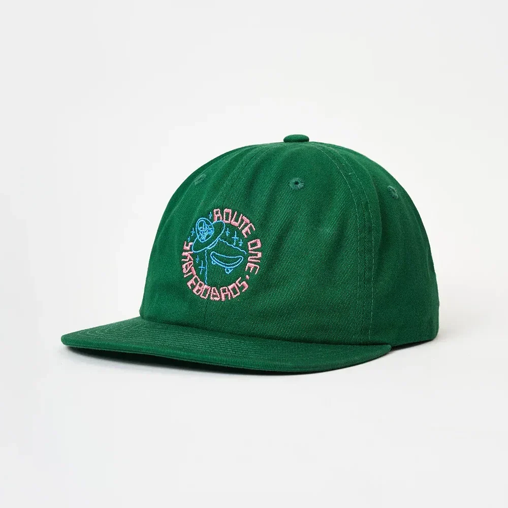 Angled front view of an unstructured green cotton twill 6-panel dad hat featuring a flat brim and colorful circular "Route One Skateboards" embroidery.