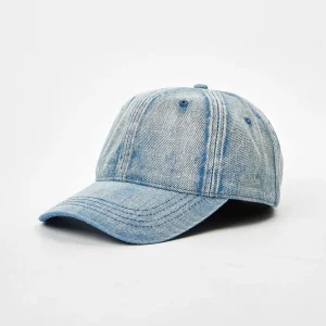 Angled front view of an unstructured light blue washed denim 6-panel dad hat featuring a pre-curved brim and vintage acid wash texture.