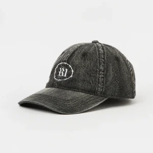 Angled front view of an unstructured washed black denim 6-panel dad hat featuring a pre-curved brim and white "R1" barbed wire embroidery.
