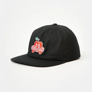 Front three-quarter view of a black unstructured cotton twill flat brim cap featuring multi-color red, white, and green cartoon apple embroidery on the front panel, with visible low-profile crown shape and flat visor angle.